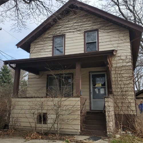 two-story tan house from front with overhang over front porch