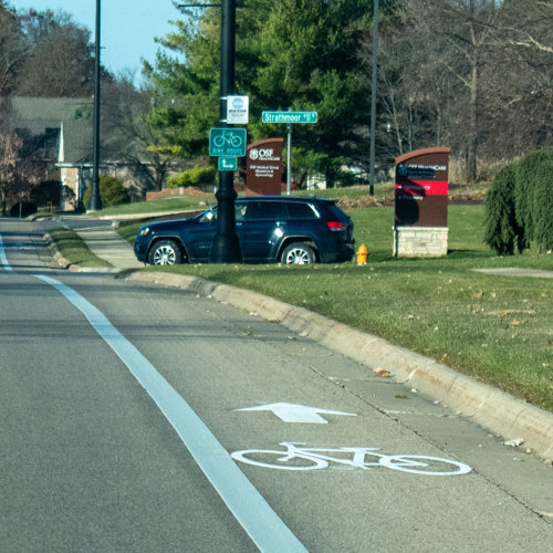 Focus on bike lane with car at intersection in the background.