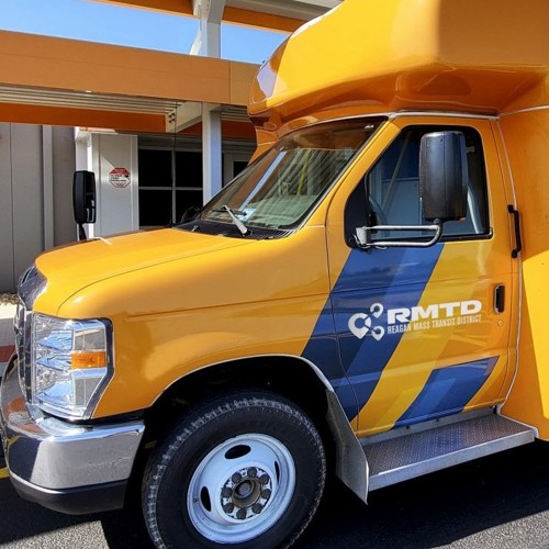 Closeup of front of yellow bus with one blue diagonal stripe and white Reagan Mass Transit District logo