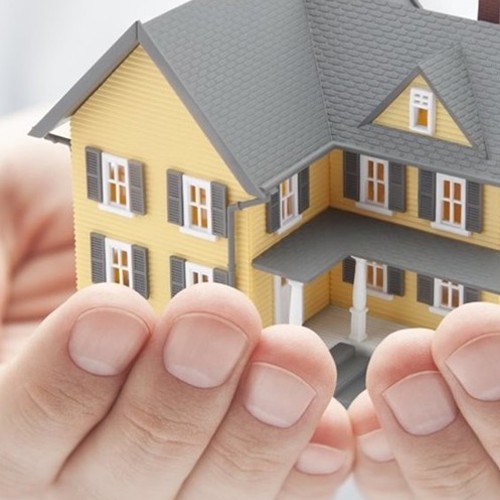 cupped hands holding a model of a yellow two-story house
