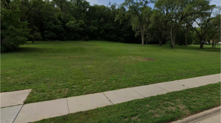 open grassy lot with sidewalk bordering road