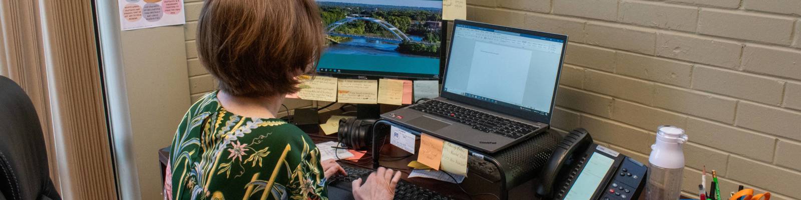 Janna Bailey, R1 Grant Specialist, sits at desk working on laptop. Picture taken from behind.